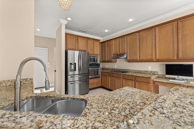kitchen with appliances with stainless steel finishes, light stone counters, a sink, under cabinet range hood, and ornamental molding