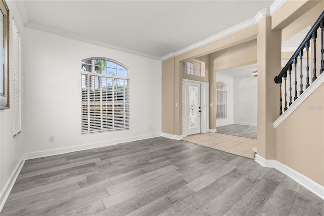 entrance foyer with baseboards, ornamental molding, wood finished floors, and stairway