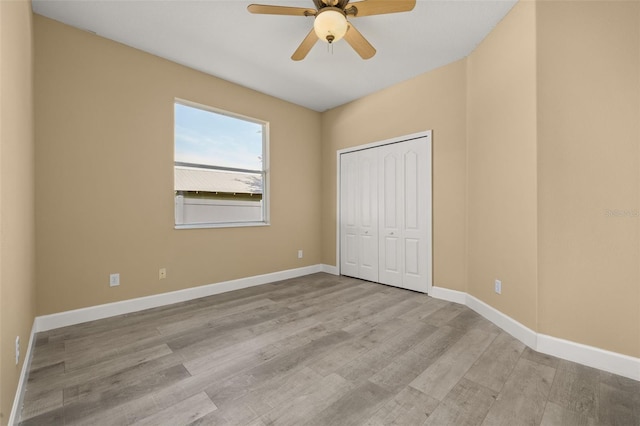 unfurnished bedroom featuring baseboards, ceiling fan, wood finished floors, and a closet