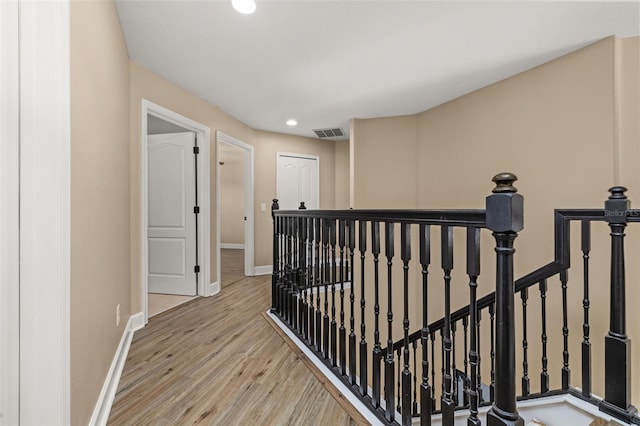 hallway featuring recessed lighting, baseboards, an upstairs landing, wood finished floors, and visible vents