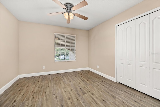 unfurnished bedroom featuring baseboards, wood finished floors, and a closet