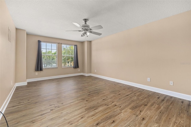 spare room featuring a textured ceiling, ceiling fan, baseboards, and wood finished floors