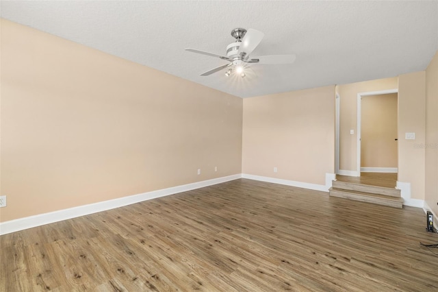 empty room featuring a ceiling fan, baseboards, and wood finished floors