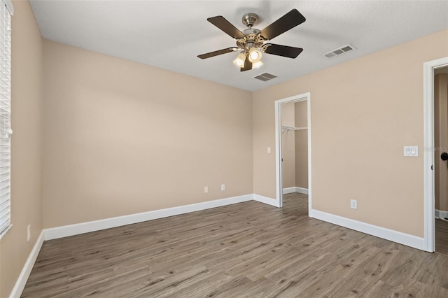 unfurnished bedroom with baseboards, wood finished floors, and visible vents