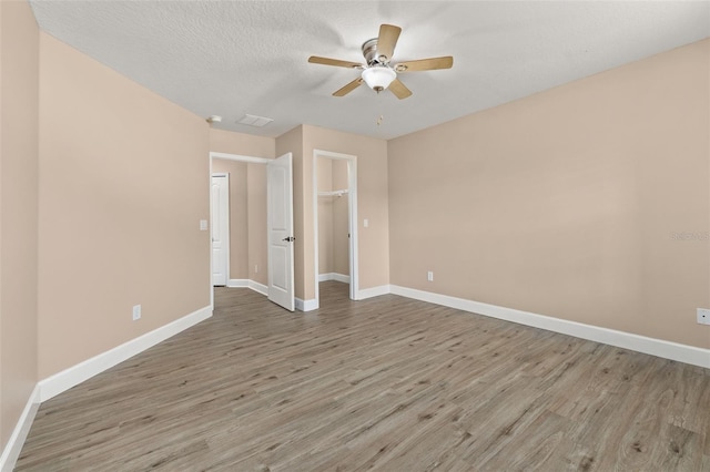 unfurnished bedroom featuring baseboards, a ceiling fan, wood finished floors, and visible vents