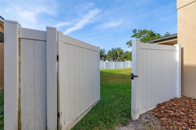 view of gate featuring fence and a yard
