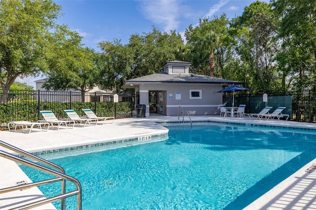 community pool featuring a patio, an outdoor structure, and fence
