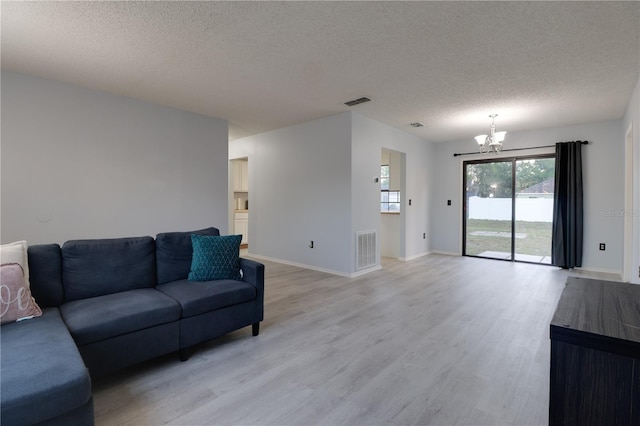 312 Oak Track Ter, Ocala, FL 34472 - living room featuring a textured ceiling, light wood-type flooring, visible vents, baseboards, and a notable chandelier