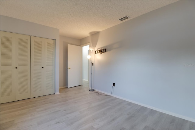 312 Oak Track Ter, Ocala, FL 34472 - unfurnished bedroom with light wood-style floors, visible vents, a closet, and a textured ceiling