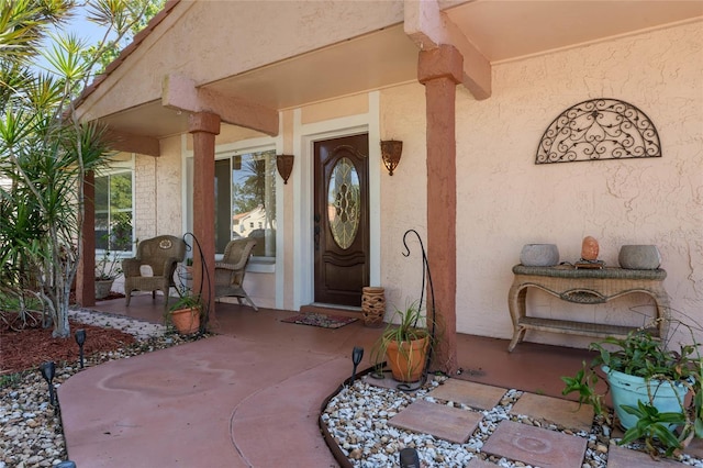 view of exterior entry with covered porch and stucco siding