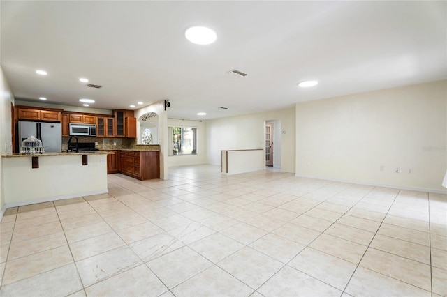 kitchen with a kitchen bar, visible vents, appliances with stainless steel finishes, open floor plan, and glass insert cabinets