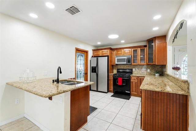 kitchen featuring visible vents, a peninsula, brown cabinets, a sink, and appliances with stainless steel finishes