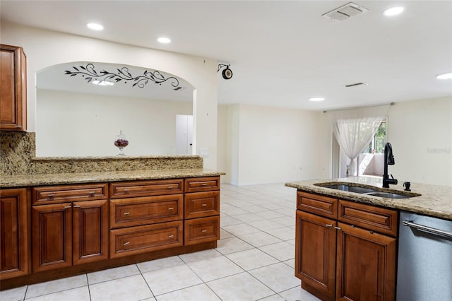 kitchen featuring light stone countertops, arched walkways, light tile patterned floors, a sink, and dishwasher