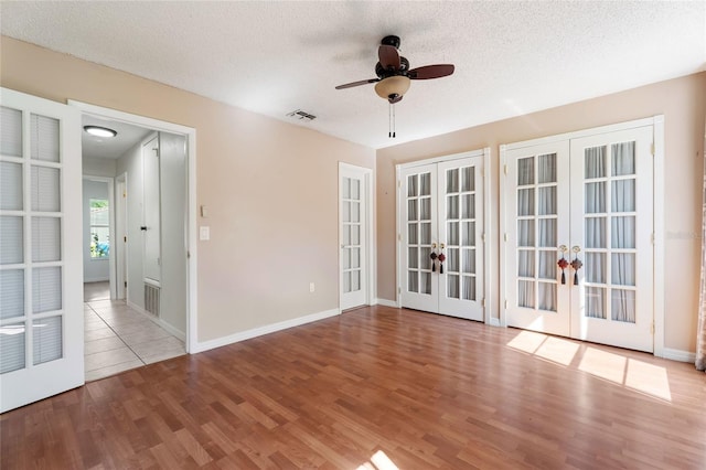 unfurnished room featuring ceiling fan, a textured ceiling, french doors, wood finished floors, and visible vents