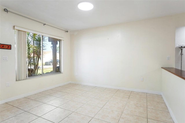 empty room featuring baseboards and light tile patterned floors