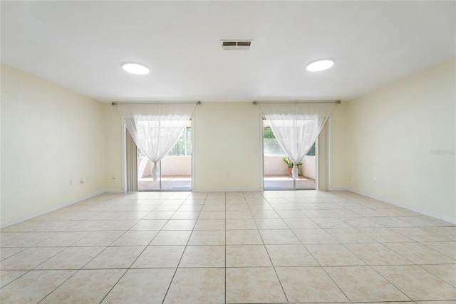 empty room with baseboards, light tile patterned flooring, and visible vents