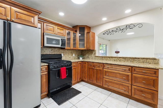 kitchen featuring brown cabinetry, appliances with stainless steel finishes, and light stone counters