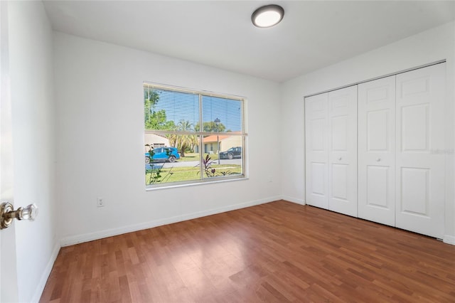 unfurnished bedroom with baseboards, a closet, and wood finished floors
