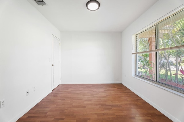 empty room with baseboards, visible vents, and wood finished floors