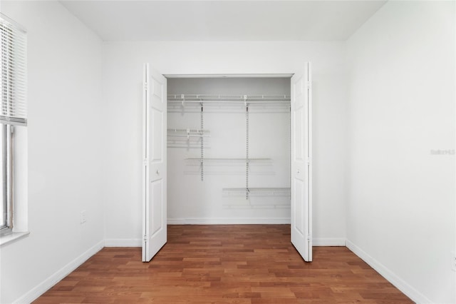 unfurnished bedroom with a closet, baseboards, and wood finished floors