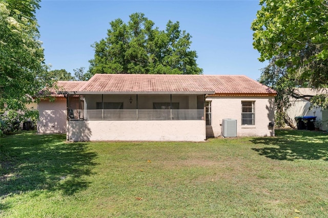 back of house featuring stucco siding, a yard, central AC, and a tile roof