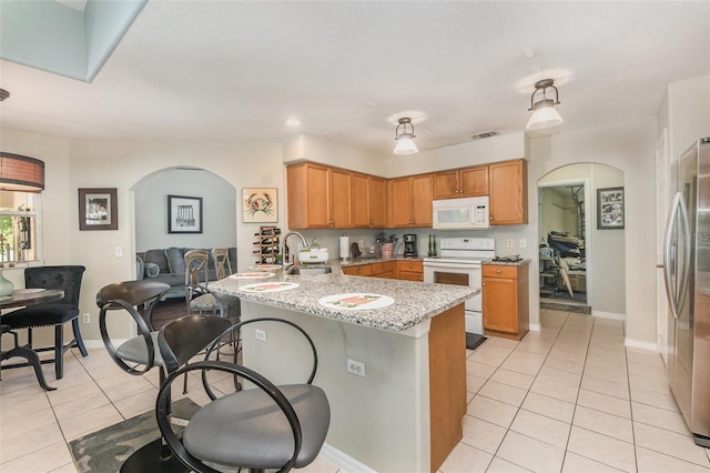 11506 Clair Pl, Clermont, FL 34711 - kitchen with light tile patterned flooring, white appliances, a peninsula, and arched walkways