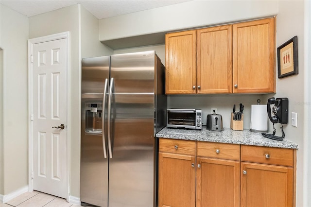 11506 Clair Pl, Clermont, FL 34711 - kitchen featuring light tile patterned floors, stainless steel refrigerator with ice dispenser, light stone counters, baseboards, and a toaster
