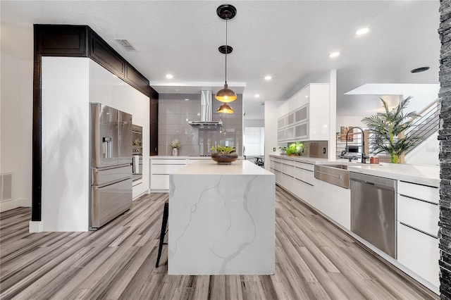 kitchen featuring a sink, visible vents, ventilation hood, a kitchen island, and appliances with stainless steel finishes
