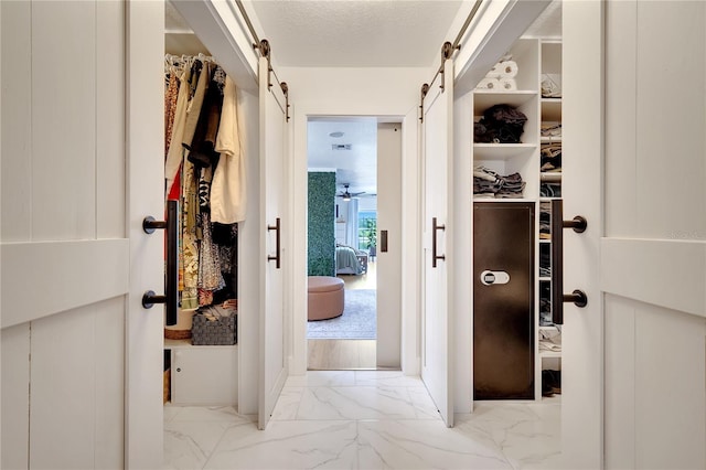 spacious closet with a barn door and marble finish floor