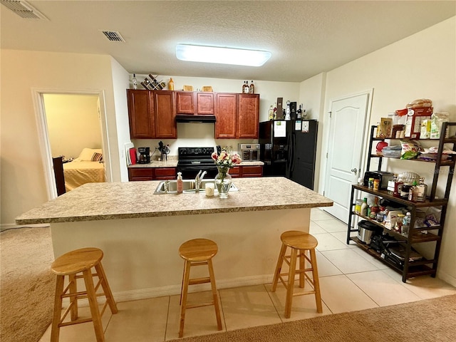 3702 Maidencain St, Clermont, FL 34714 - kitchen featuring light countertops, visible vents, a kitchen bar, range hood, and black appliances
