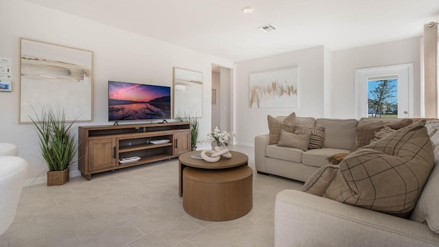 living area featuring light tile patterned floors, visible vents, and baseboards