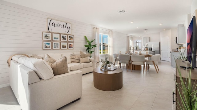 living room featuring visible vents, recessed lighting, light tile patterned flooring, and wood walls