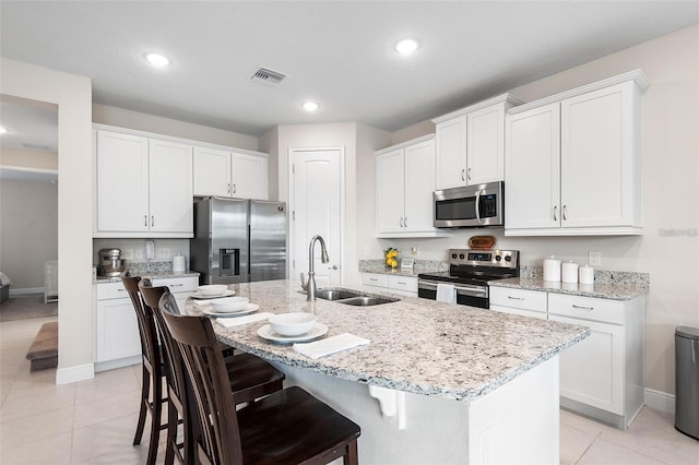 416 Southfield St, Kissimmee, FL 34747 - kitchen with visible vents, a sink, a center island with sink, a breakfast bar area, and stainless steel appliances