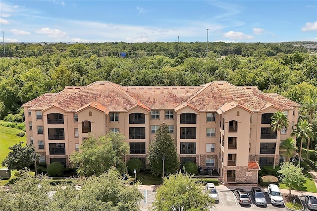 view of property featuring a view of trees and uncovered parking