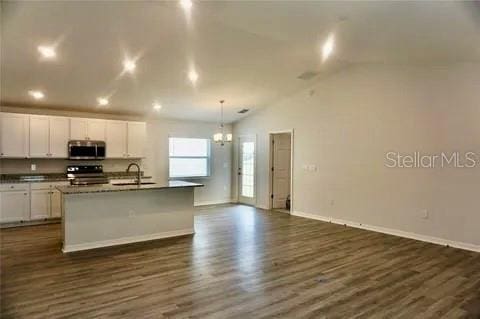 2607 Tulip Dr, Davenport, FL 33837 - kitchen featuring a sink, appliances with stainless steel finishes, dark wood finished floors, white cabinetry, and a center island with sink