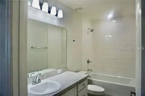 2607 Tulip Dr, Davenport, FL 33837 - bathroom featuring visible vents, toilet, vanity, and  shower combination