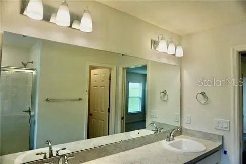 2607 Tulip Dr, Davenport, FL 33837 - bathroom featuring a shower with shower door, double vanity, and a sink