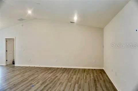 2607 Tulip Dr, Davenport, FL 33837 - spare room with wood finished floors, baseboards, and lofted ceiling
