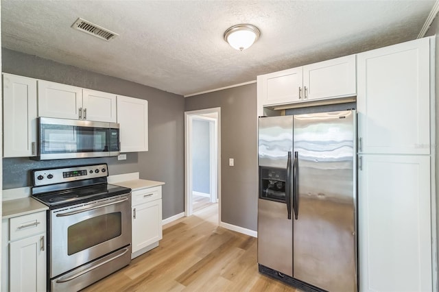 1234 Parker Ave, Deltona, FL 32725 - kitchen featuring stainless steel appliances, white cabinets, light wood finished floors, visible vents, and a textured ceiling