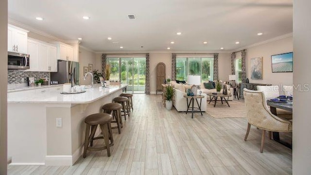 25126 Calusa Dr, Punta Gorda, FL 33955 - kitchen featuring light wood-type flooring, ornamental molding, a breakfast bar, stainless steel appliances, and backsplash