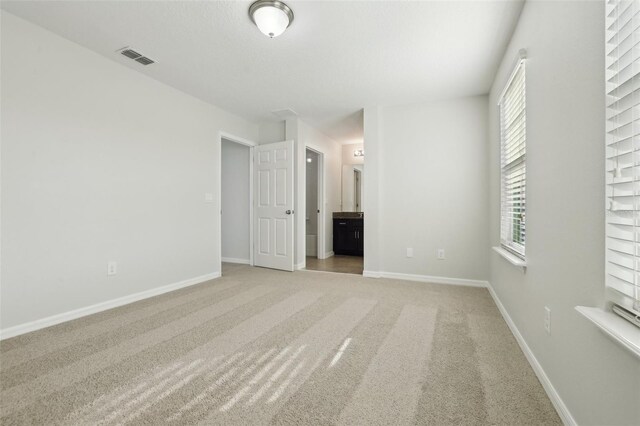 611 Marsh Reed Dr, Winter Garden, FL 34787 - unfurnished bedroom featuring visible vents, baseboards, connected bathroom, and light colored carpet