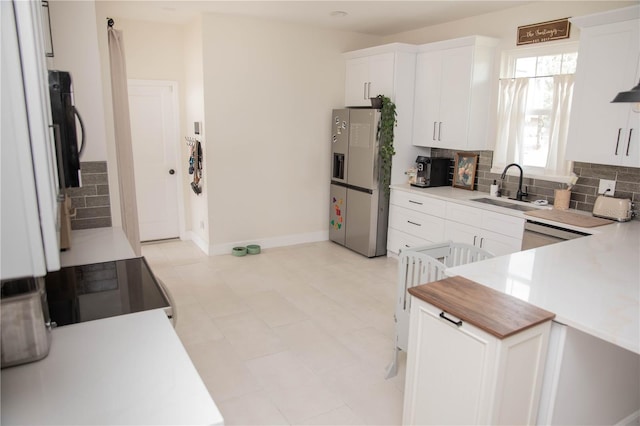 kitchen featuring backsplash, a sink, white cabinets, and stainless steel fridge