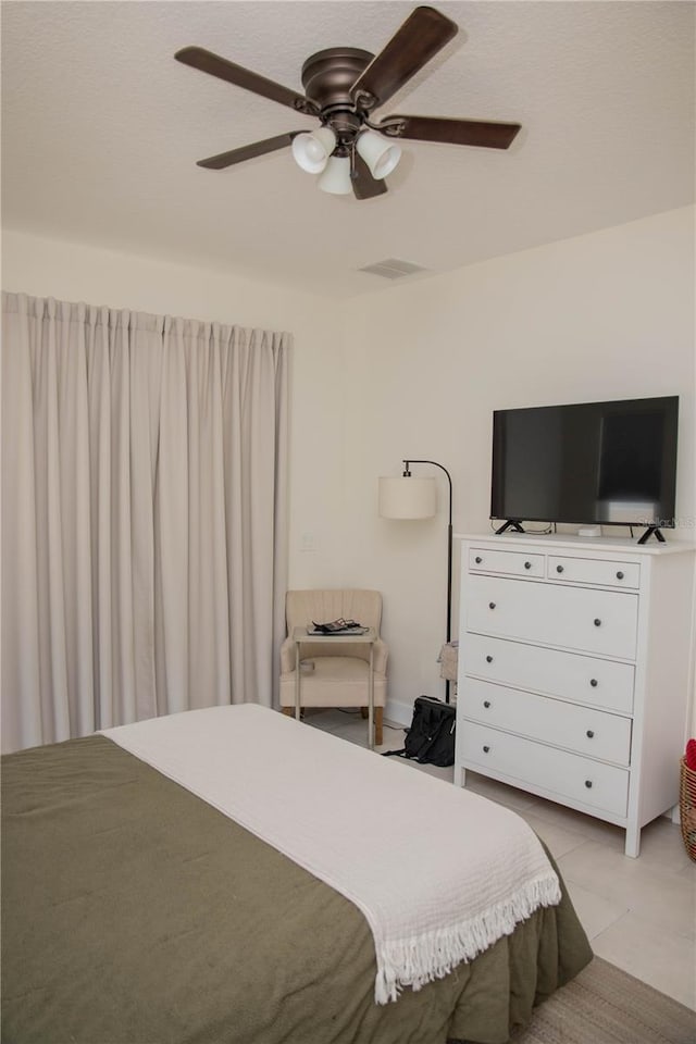 bedroom with light tile patterned floors, visible vents, and ceiling fan