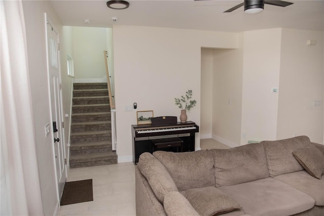 living area with baseboards, stairs, and ceiling fan