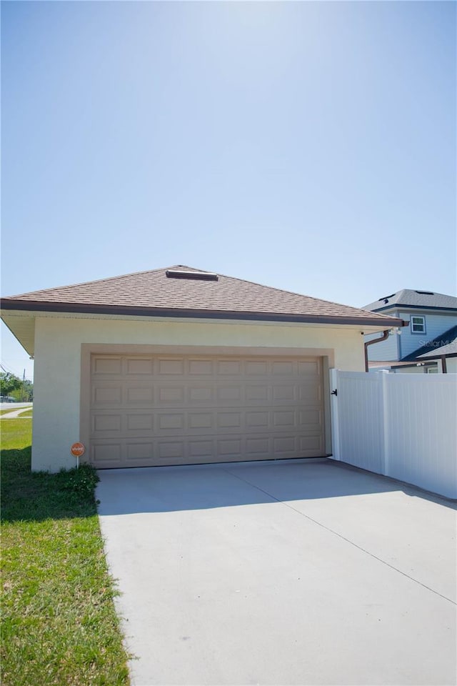 garage featuring fence and concrete driveway