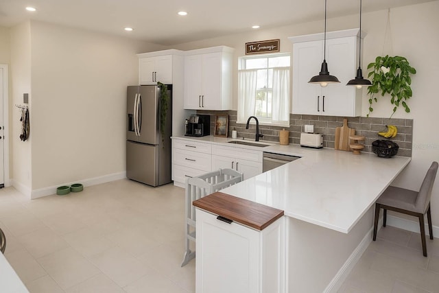 900 S Maple Ave, Sanford, FL 32771 - kitchen with stainless steel appliances, a sink, a breakfast bar area, backsplash, and white cabinetry