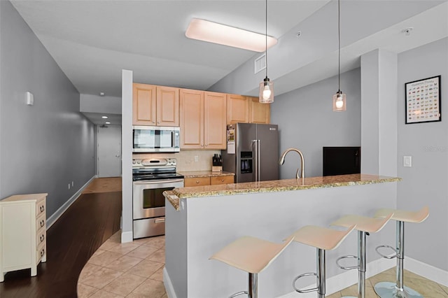 101 S Eola Dr Unit 1018, Orlando, FL 32801 - kitchen featuring stainless steel appliances, a peninsula, light brown cabinets, and a breakfast bar area