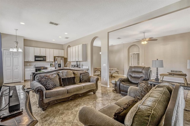 living room with recessed lighting, visible vents, arched walkways, baseboards, and ceiling fan with notable chandelier