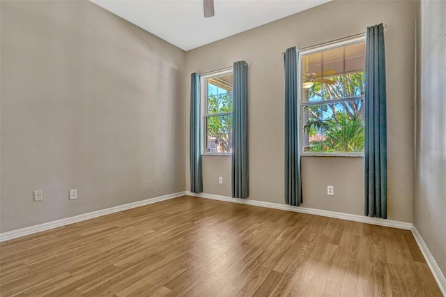 empty room featuring wood finished floors, baseboards, and ceiling fan