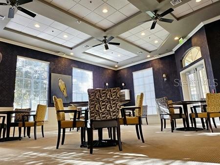 carpeted dining area featuring wallpapered walls, visible vents, a ceiling fan, and ornamental molding
